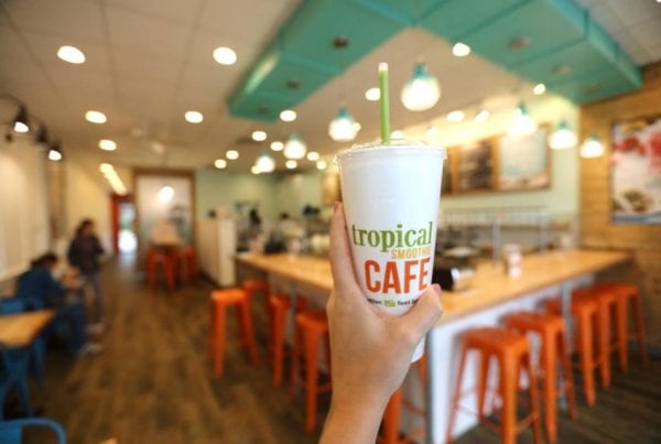 Interior of a Tropical Smoothie Cafe with someone holding up a smoothie cup