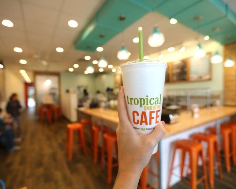 Interior of a Tropical Smoothie Cafe with someone holding up a smoothie cup
