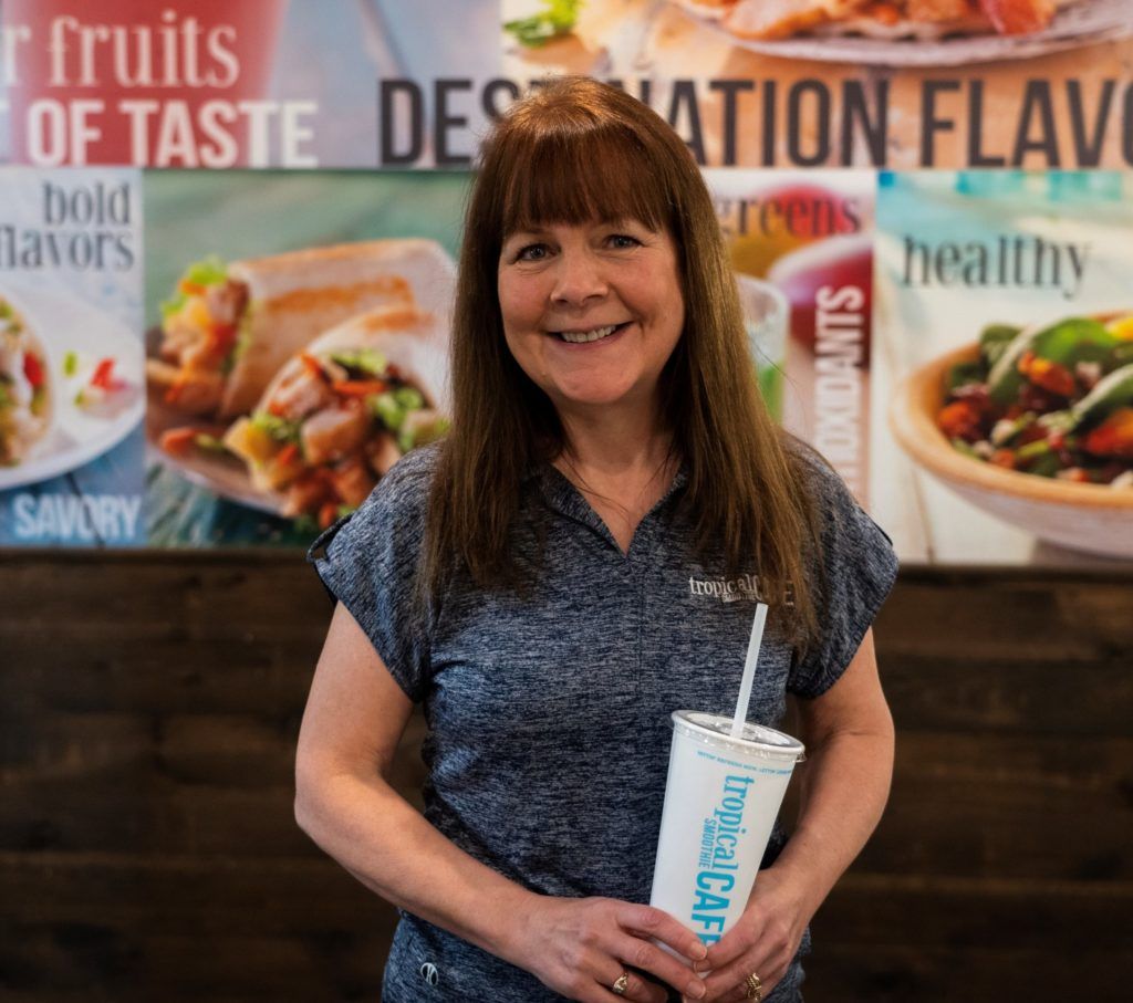 Tropical Smoothie Cafe franchise owner laura jankowski holing a smoothie cup and smiling