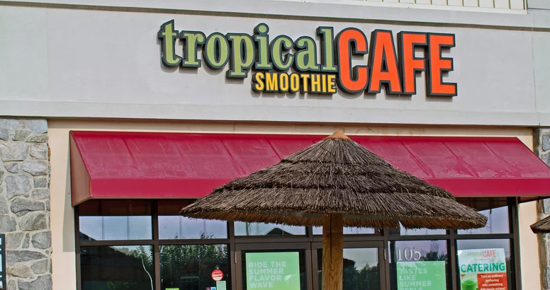 Exterior of Tropical smoothie location with umbrella in front.