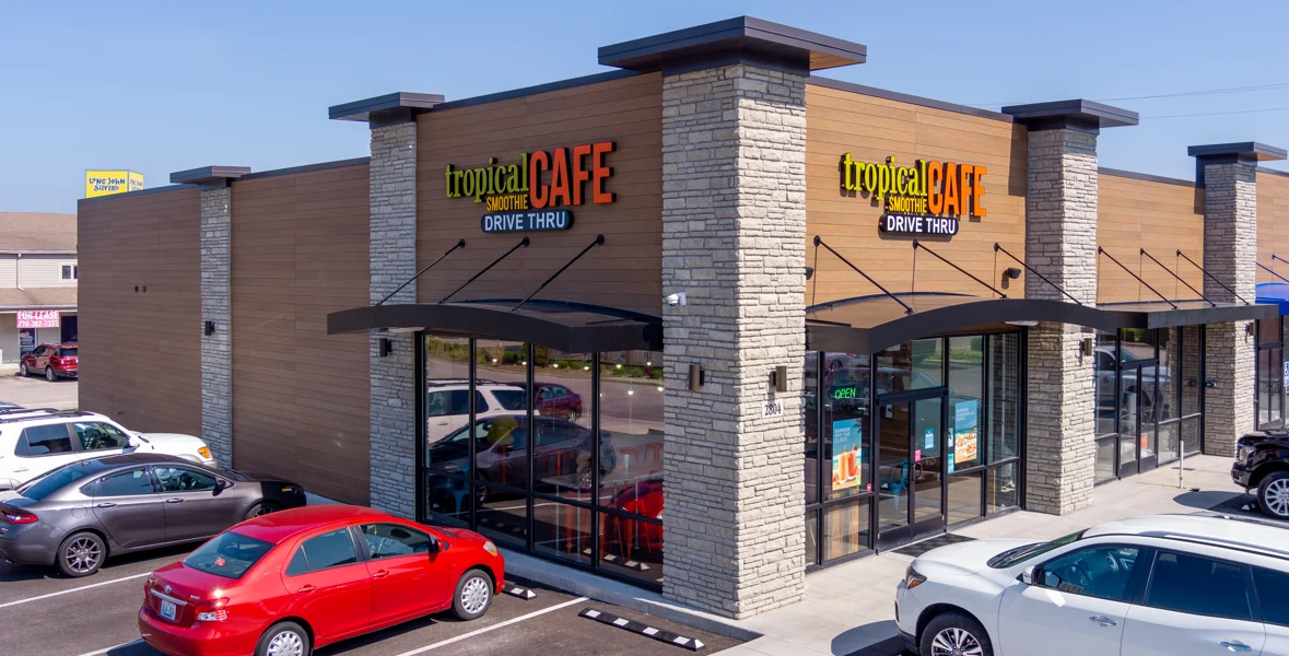 exterior of tropical smoothie cafe location on a corner with cars parked out front
