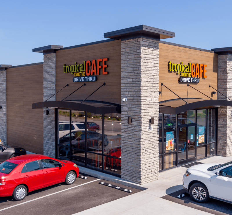 exterior of tropical smoothie cafe location on a corner with cars parked out front